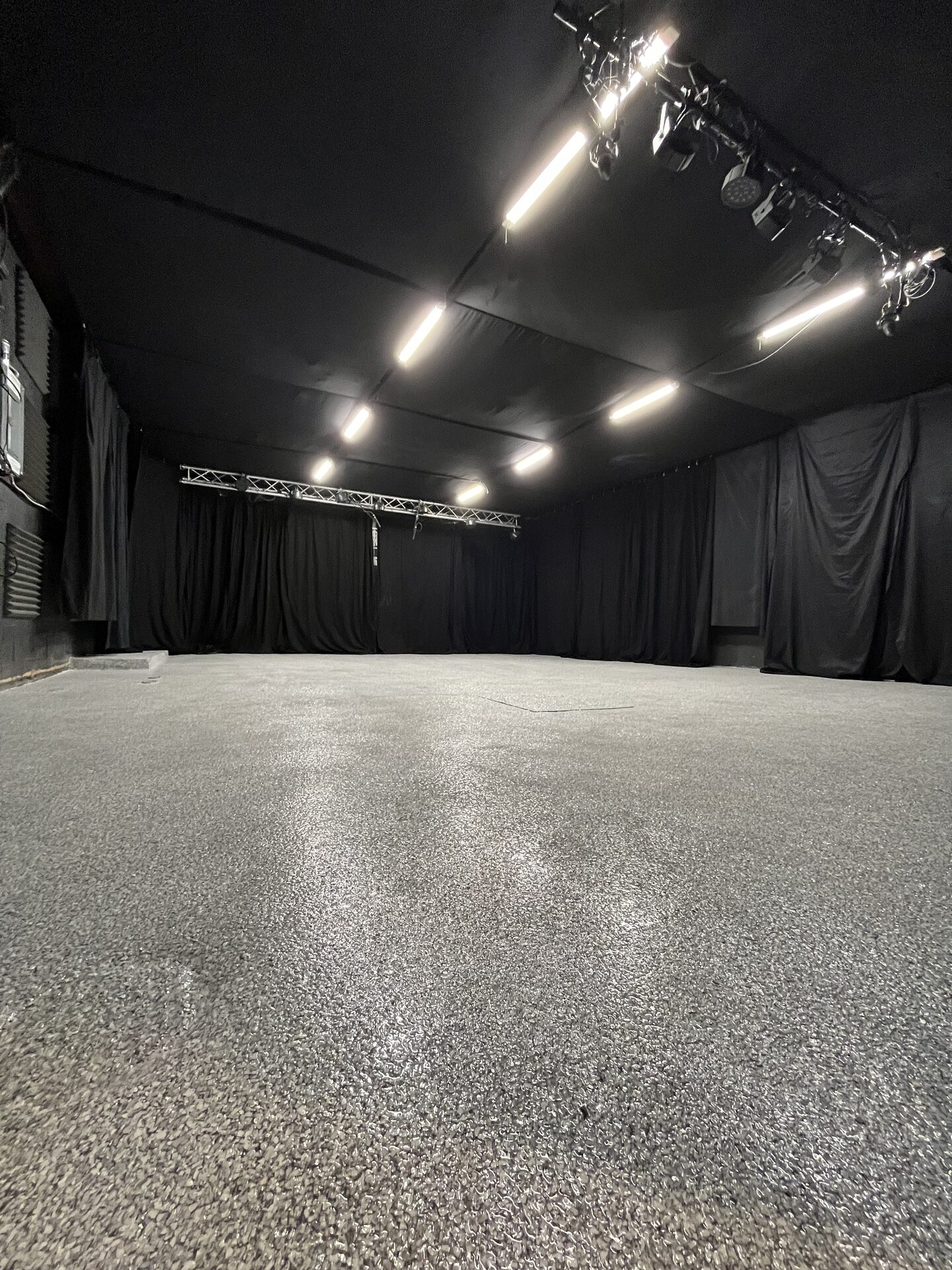 Stripped 700 sqft Rock Mill room from the back wall showing fresh carpet and full ceiling height