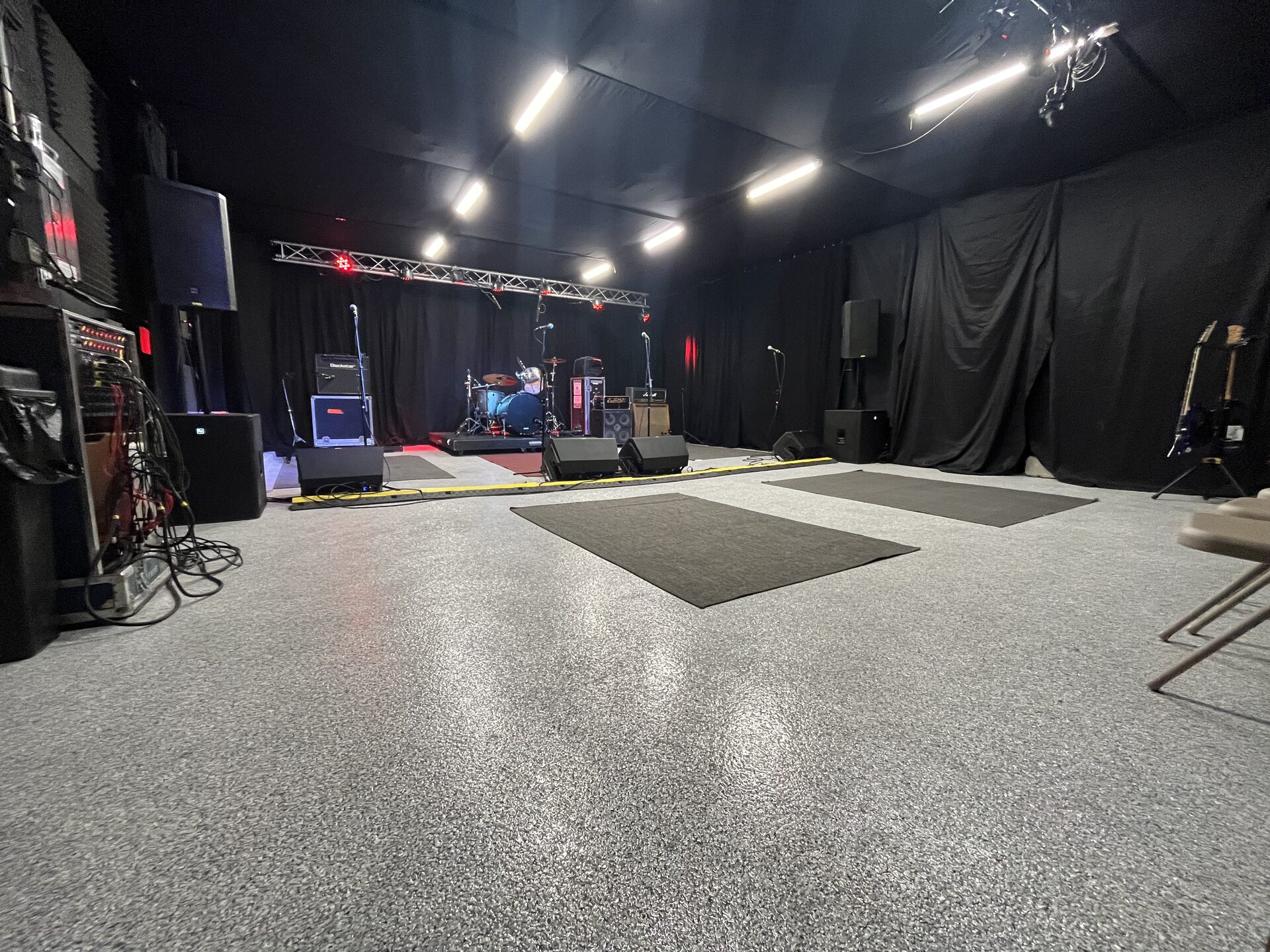 Wide view of Rock Mill room with EV PA speakers, mic stands, and bass rig on stage